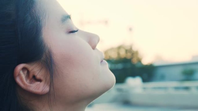 迷人的亚洲女运动员闭上眼睛，在公园呼吸新鲜空气。健康健康生活方式概念。