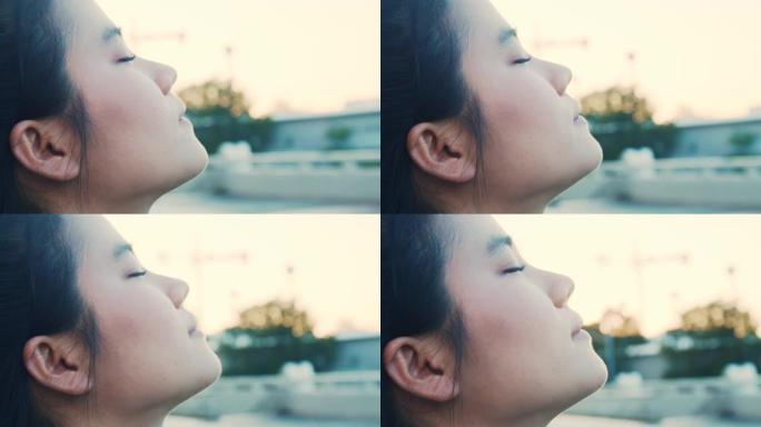 迷人的亚洲女运动员闭上眼睛，在公园呼吸新鲜空气。健康健康生活方式概念。