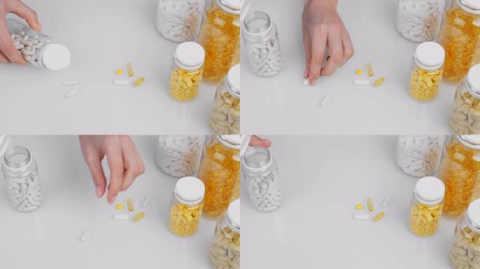 特写女人的手倒白色胶囊瓶表面，把它放在白色背景上的其他药丸。营养补充剂，瓶中的维生素。欧米茄3，多种
