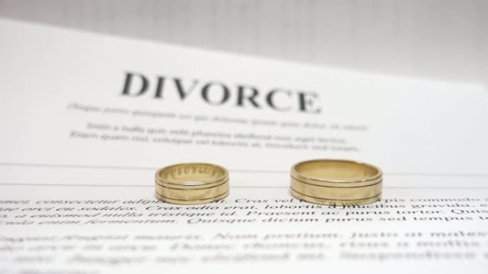 离婚概念视频，中间有两个金婚戒指，以离婚为背景。软聚焦。