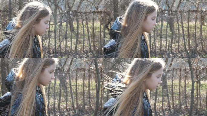 早春时，带背包的可爱女学生沿着花园附近的小径走。金发碧眼的小姑娘走在人行道上。不快乐的小孩在去学校的