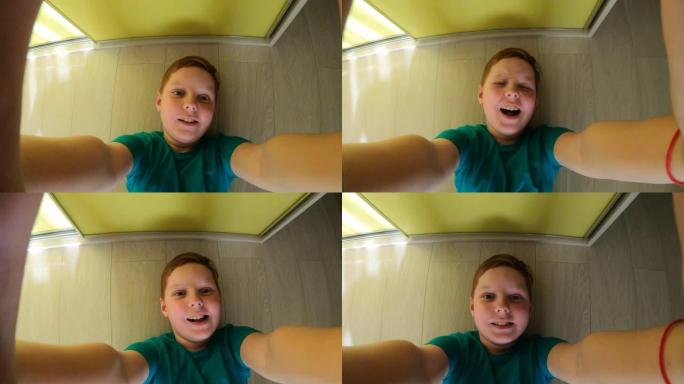 微笑的红发小男孩的男性面孔，雀斑躺在房间的地板上，在GoPro上拍摄自己。快乐的姜孩子的肖像在家里玩