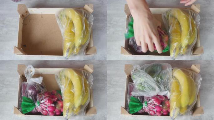女人手把包装好的水果和蔬菜放进盒子里