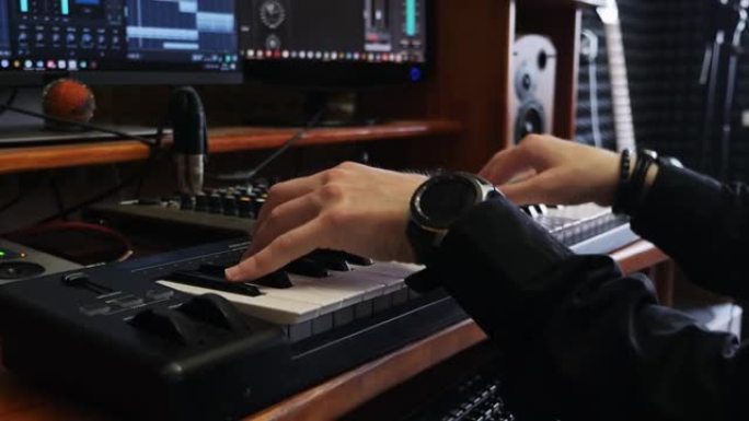 音乐家词曲作者在家庭音乐工作室演奏钢琴midi键盘。声音制作人在录音室创作流行摇滚歌曲。近距离弹奏电