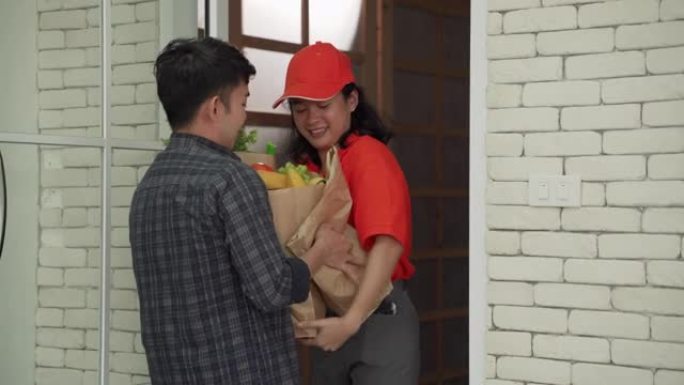 亚洲女孩送货员将蔬菜食品带到家门口，服务工作，在线订购食品。