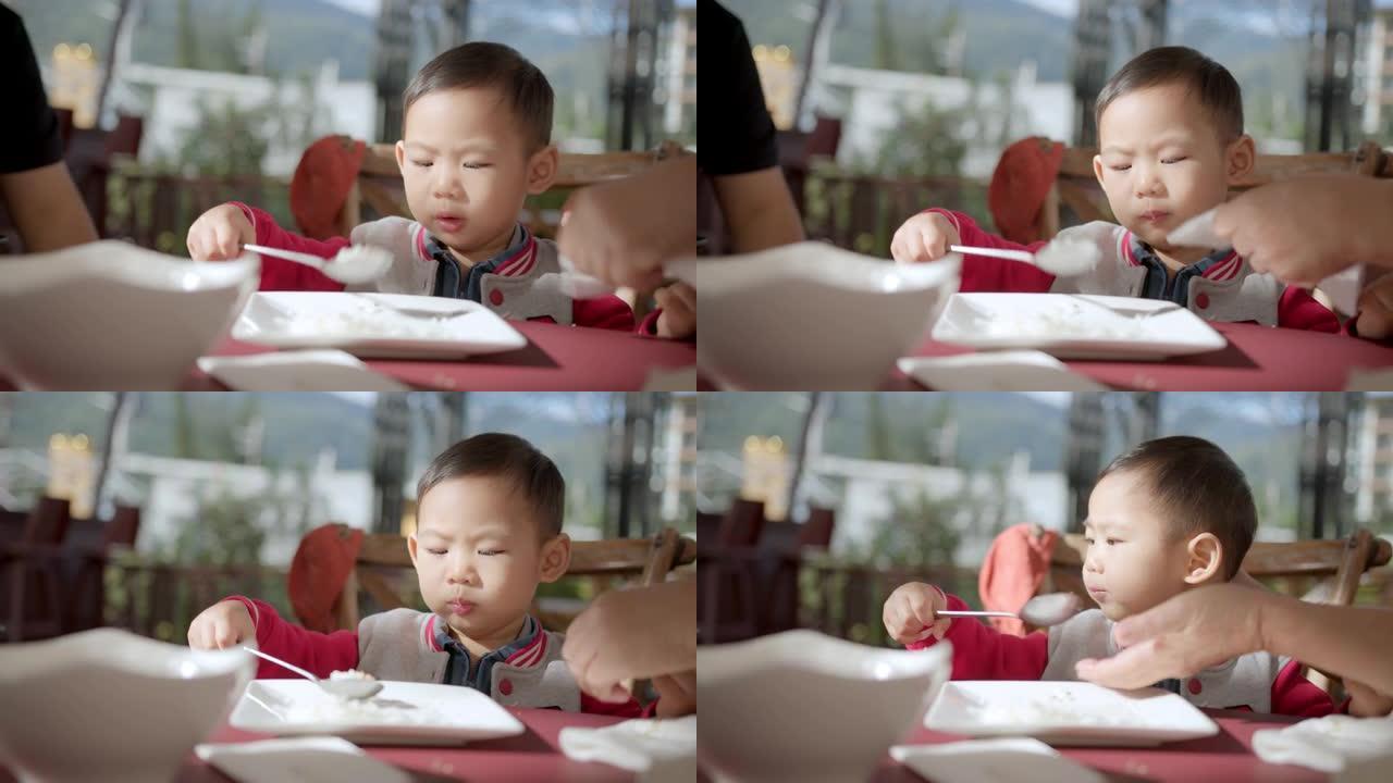 特写亚洲祖母手喂孙子男孩子吃早餐健康生活理念