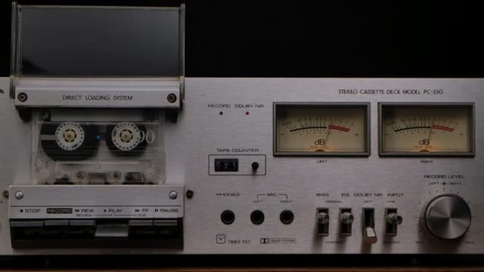 80年代的老式卡带播放器甲板。立体声录音机，带有旋转盒式磁带，控件，仪表板和黑色工作室背景上的按钮。