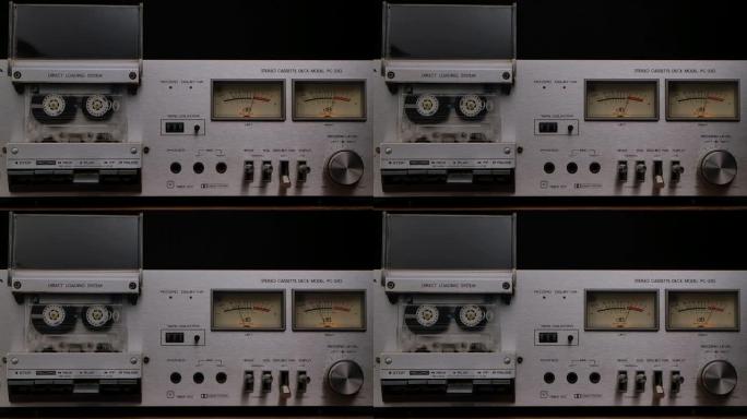 80年代的老式卡带播放器甲板。立体声录音机，带有旋转盒式磁带，控件，仪表板和黑色工作室背景上的按钮。