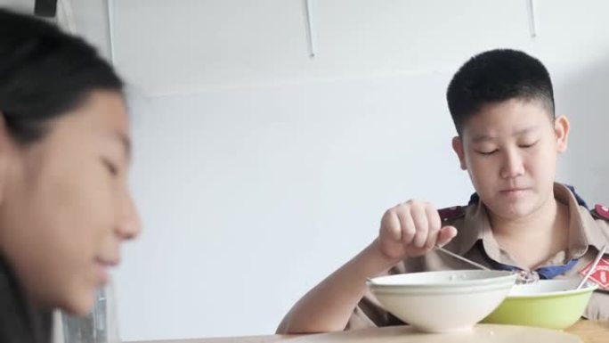 快乐的亚洲童子军和他的妹妹在早上上学前一起享用早餐和交谈，生活方式理念。