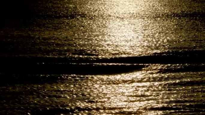 低调的灯光。波浪平稳滚动，夕阳光在水中反射。平静与宁静的背景概念。