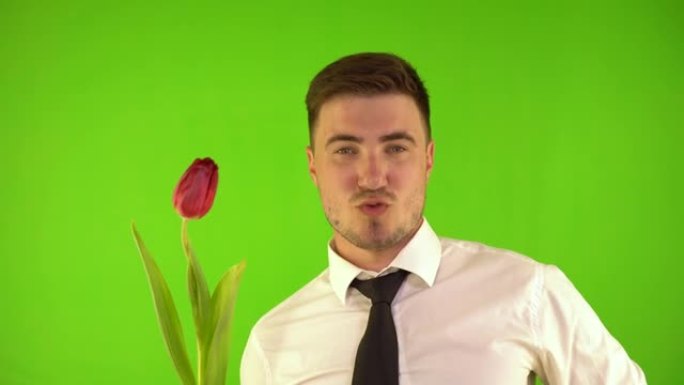 性感的男人穿着白色衬衫，嘴里含着一朵花，给它一个吻。调情的人