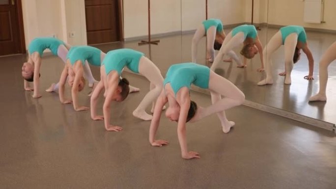 四个非常灵活的小女孩正在舞蹈室里做伸展运动。