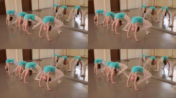 四个非常灵活的小女孩正在舞蹈室里做伸展运动。