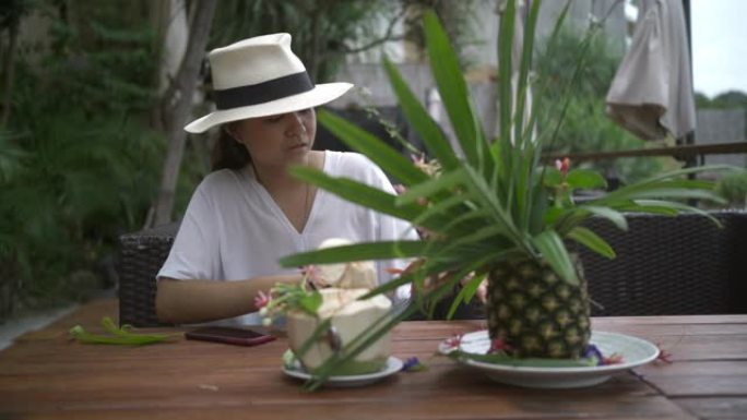 一位穿着白色连衣裙和帽子的亚洲年轻女子安排餐桌装饰户外午餐日的食物道具