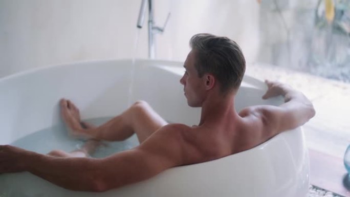 肌肉发达的运动型男人在家中的大浴缸里休息，背面视图