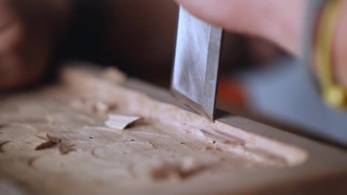 宏观。木雕师制作一个木托盘。工匠用平冲击凿子加工胡桃板