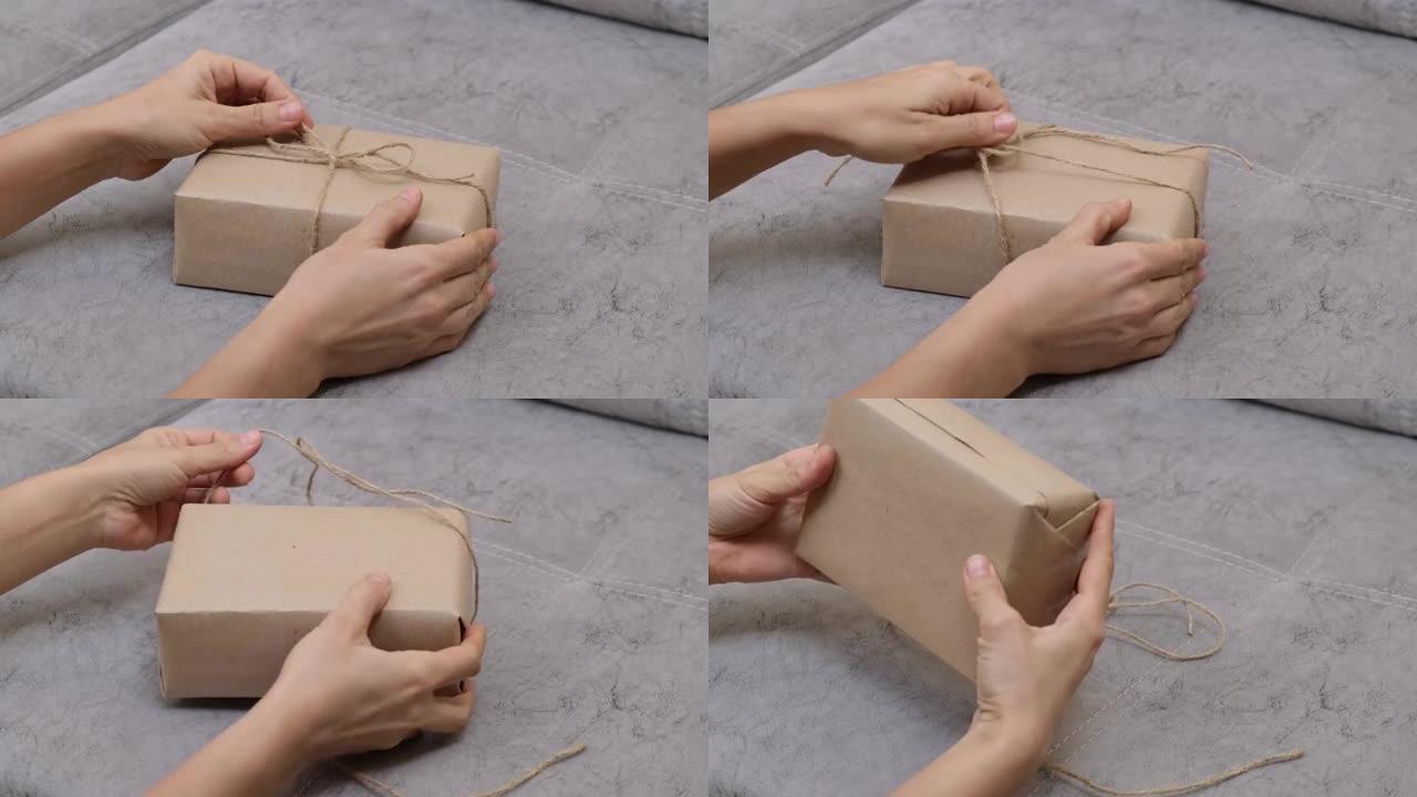 女人的手解开礼物，从礼品盒中取出黄麻绳。零浪费礼品包装