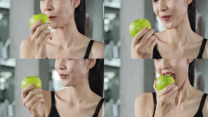 亚洲美女在健身房咬青苹果的特写。