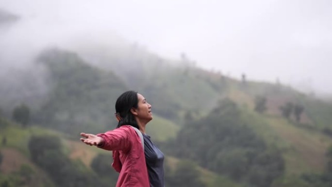 年轻的亚洲妇女快乐地呼吸着山顶上的新鲜空气