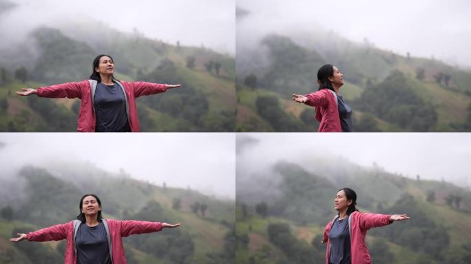 年轻的亚洲妇女快乐地呼吸着山顶上的新鲜空气