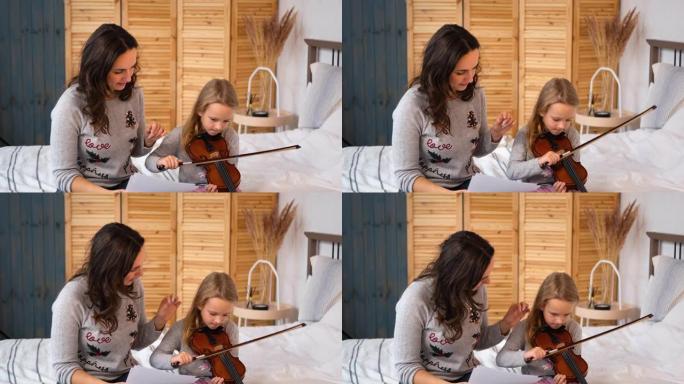 女人教小女孩在室内拉小提琴