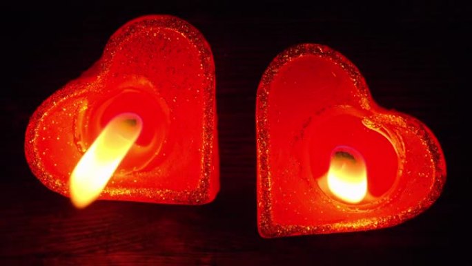 两支蜡烛在心形的黑暗木桌上一起照明