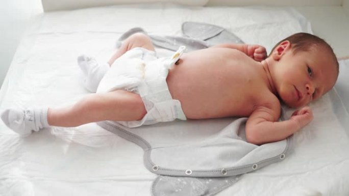 一个穿着尿布和袜子的新生婴儿躺在换衣桌上。绷带脐带。婴儿新生生命的最初时刻。