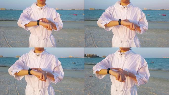 女人在沙滩上散步时使用智能手表