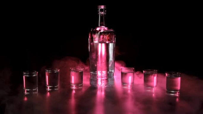 平坦的瓶子和六个完整的玻璃杯，带有伏特加，龙舌兰酒或清酒，黑色背景。红色烟雾云雾或红色蒸汽在空中漂浮