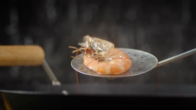 从锅中取出一只煮熟的热虾。