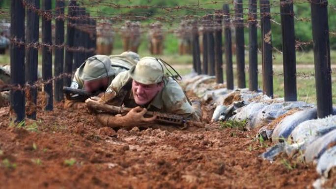 士兵们正在训练用步枪在泥泞中爬行。