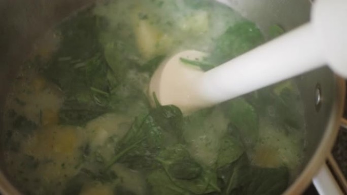 用棒搅拌器手工搅拌韭菜土豆汤