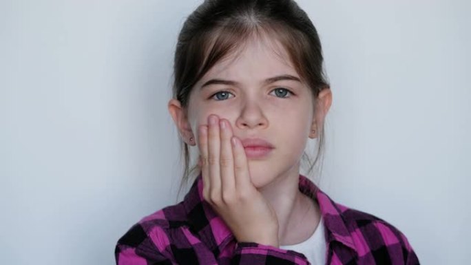 小/年轻悲伤的女孩抱着她的脸颊。牙痛，鼻窦炎。