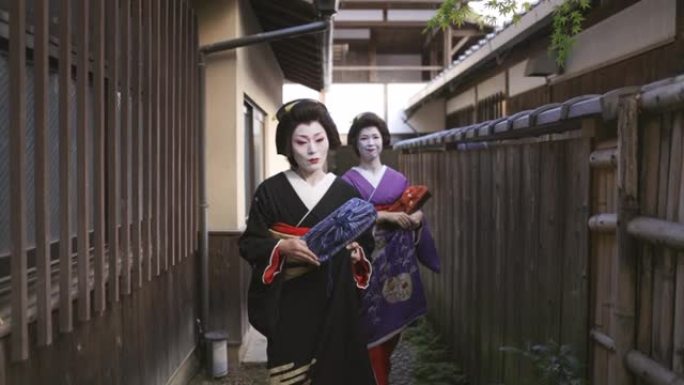 两名艺妓妇女一起走在京都Gion的狭窄街道上