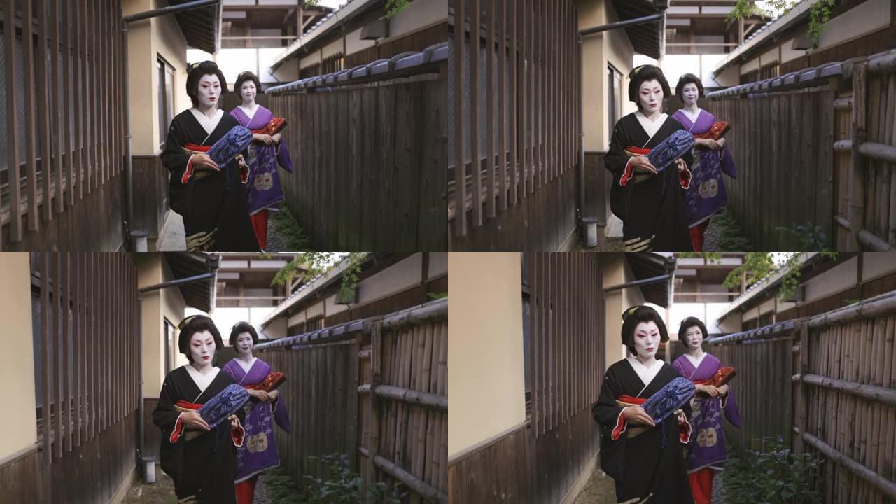两名艺妓妇女一起走在京都Gion的狭窄街道上