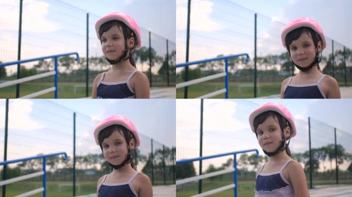一个小女孩第一次来到轮滑公园学习轮滑。一个戴着粉色安全帽的学龄前漂亮孩子的特写肖像，4k慢动作50 