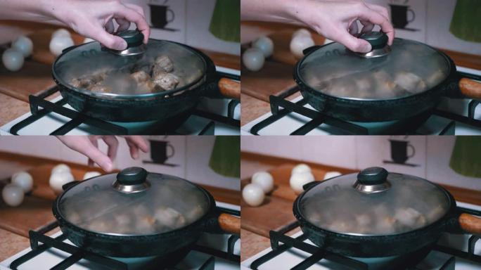 女性手打开盖子，在煎锅中检查准备就绪的肉。家庭厨房