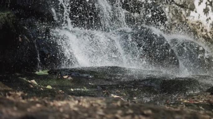 瀑布飞溅的水，美丽的水滴落在地上，山瀑布，水在大自然中飞溅，流水在山上的石头上。
