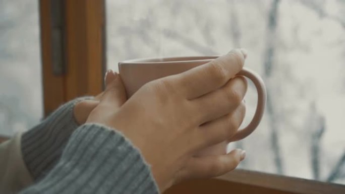冬天，在窗户附近喝杯咖啡的女孩