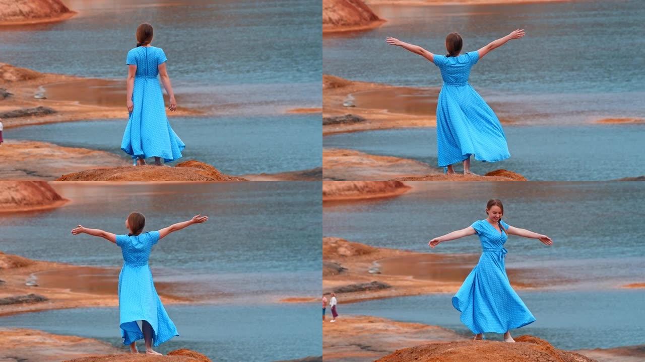 穿着蓝色连衣裙的年轻女子观看橙色粘土海滩和湖泊的景色