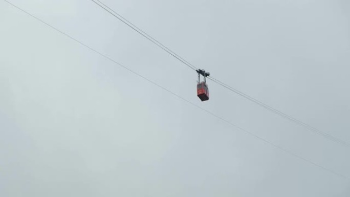 红色滑雪缆车或缆车在山顶的云层中沿缆车移动