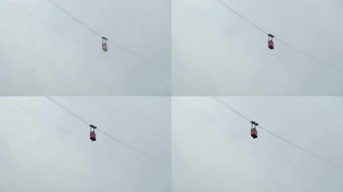 红色滑雪缆车或缆车在山顶的云层中沿缆车移动