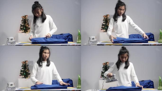 亚洲女学生熨烫她的校服，圣诞树装饰装饰背景，生活方式概念。
