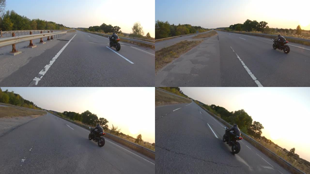 跟随骑自行车的人在日落时在乡村路上骑现代运动摩托车。摩托车手在高速公路上骑摩托车。旅途中开车的人。旅