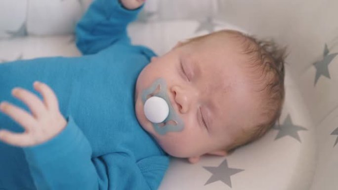 新生婴儿挥舞双手睡在家里的茧特写