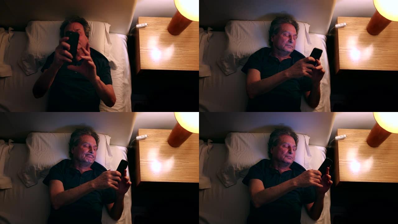 男子打开床头柜灯，拿起手机。检查智能手机屏幕的人