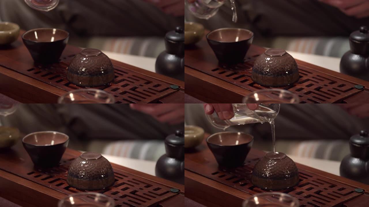 慢动作镜头，男人的手用沸水清洗茶道的陶瓷碗，以使其在装满茶之前具有必要的温度