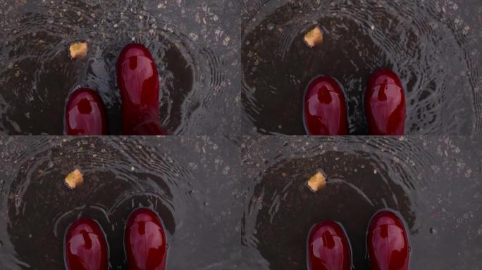 穿着橡胶红色防水靴的女人在寒冷的天气里穿过秋天的泥坑
