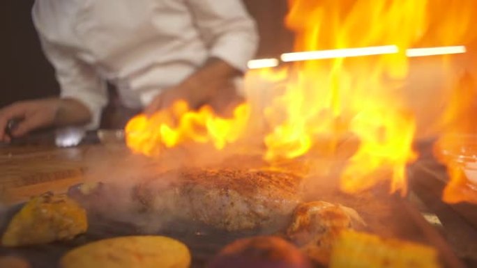 烧烤特写现代厨房的牛排。厨师在餐厅准备火烧烤盘。烤架煎锅里的火焰。烹饪美味的食物。在菜肴上加工餐点。