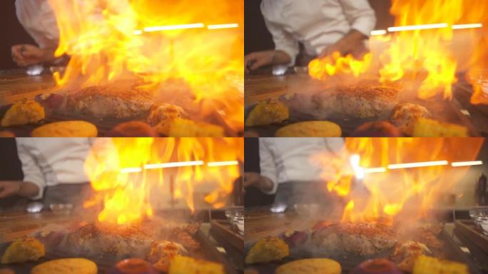 烧烤特写现代厨房的牛排。厨师在餐厅准备火烧烤盘。烤架煎锅里的火焰。烹饪美味的食物。在菜肴上加工餐点。